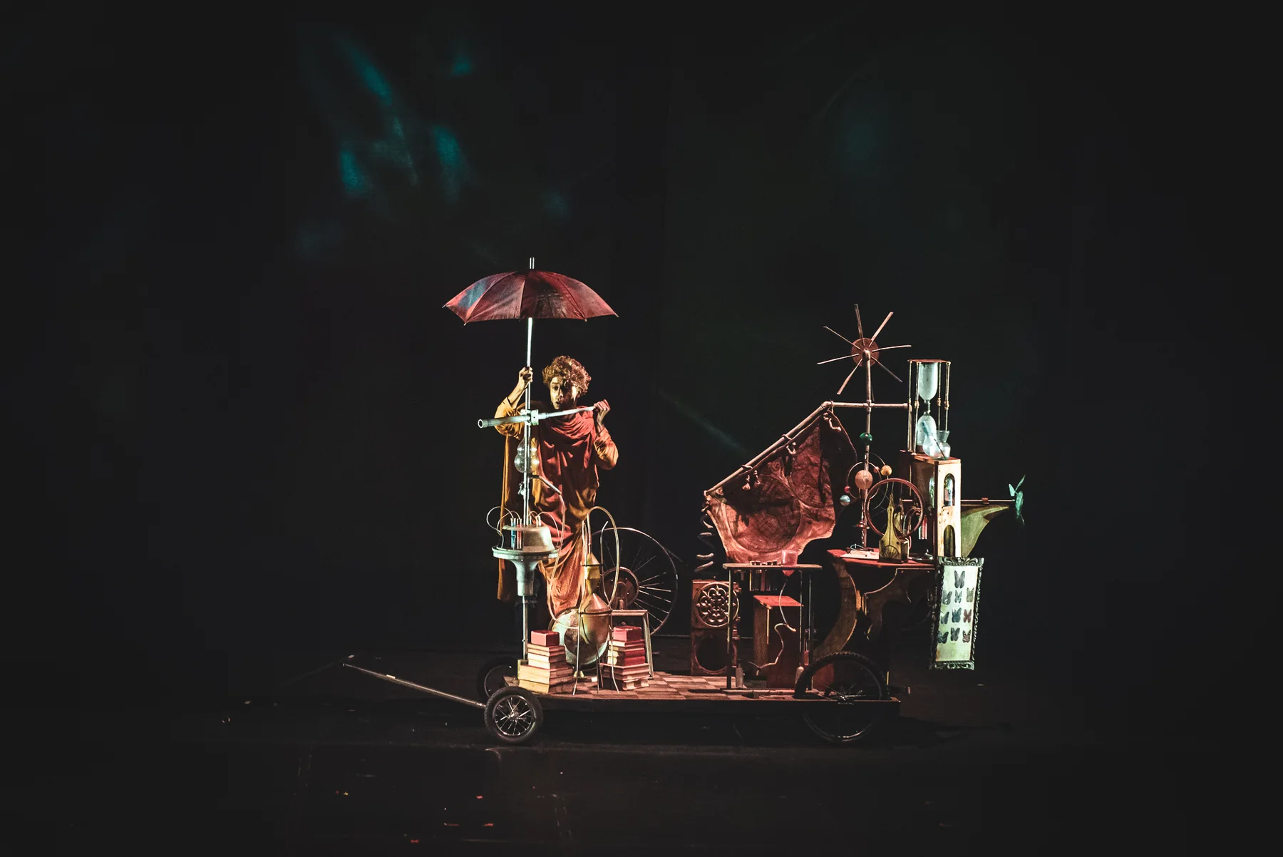 Un personaje y un dispositivo escenográfico con ruedas, objetos y mecanismos.